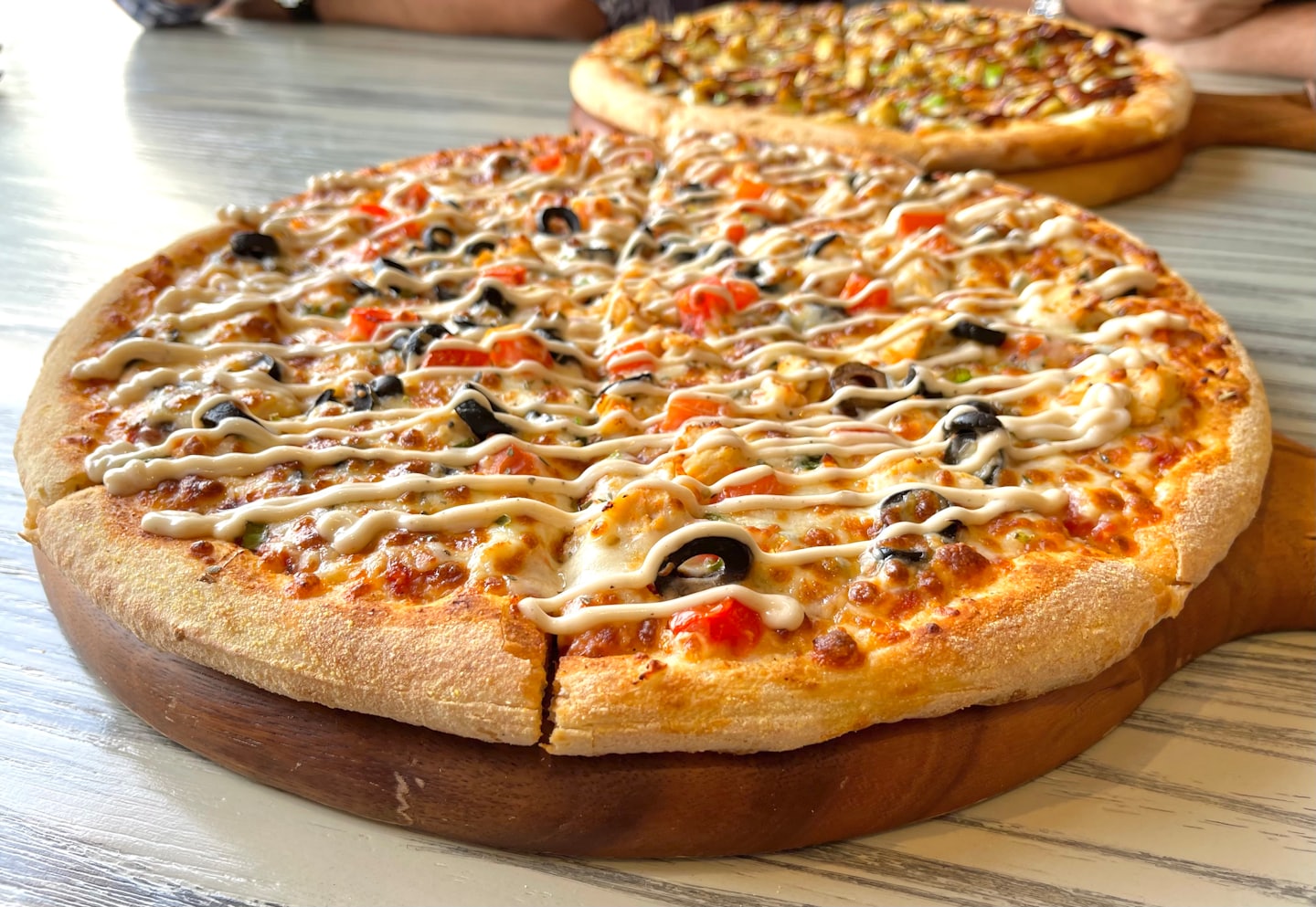 Dve čerstvo upečené pizze na drevených doskách na stole.
