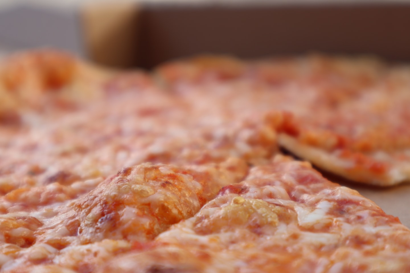 Plátky horúcej syrovej pizze s roztopenými polevami.